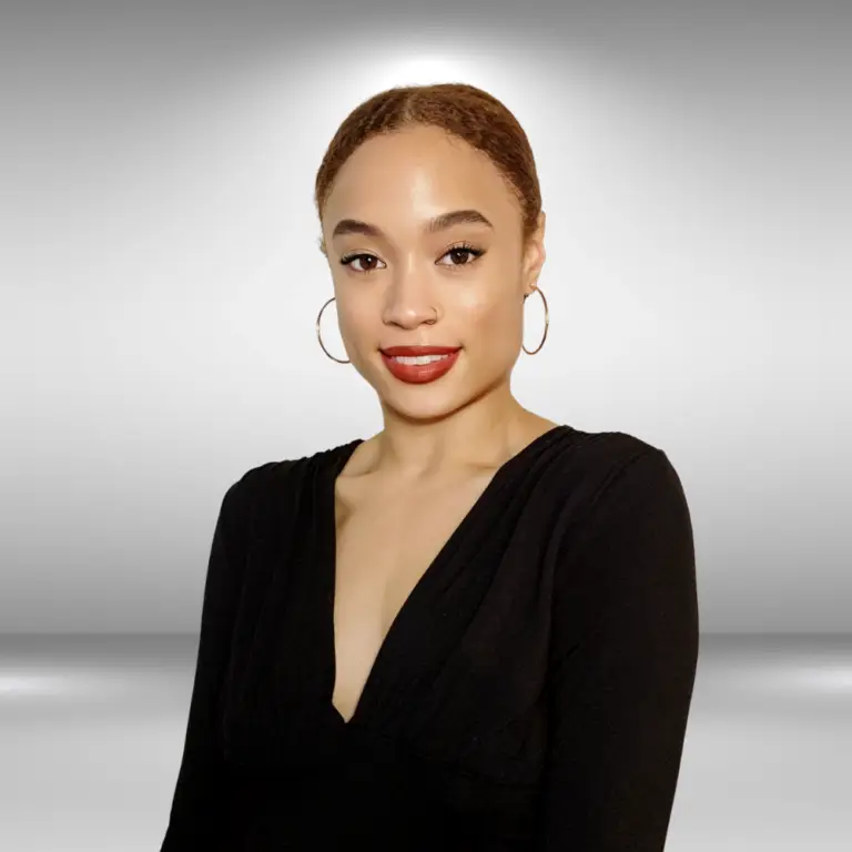 Portrait of a woman with light brown skin, wearing a black V-neck top and large hoop earrings. She has her hair pulled back and is smiling, radiating the confidence of an influencer, with a neutral gray background behind her.