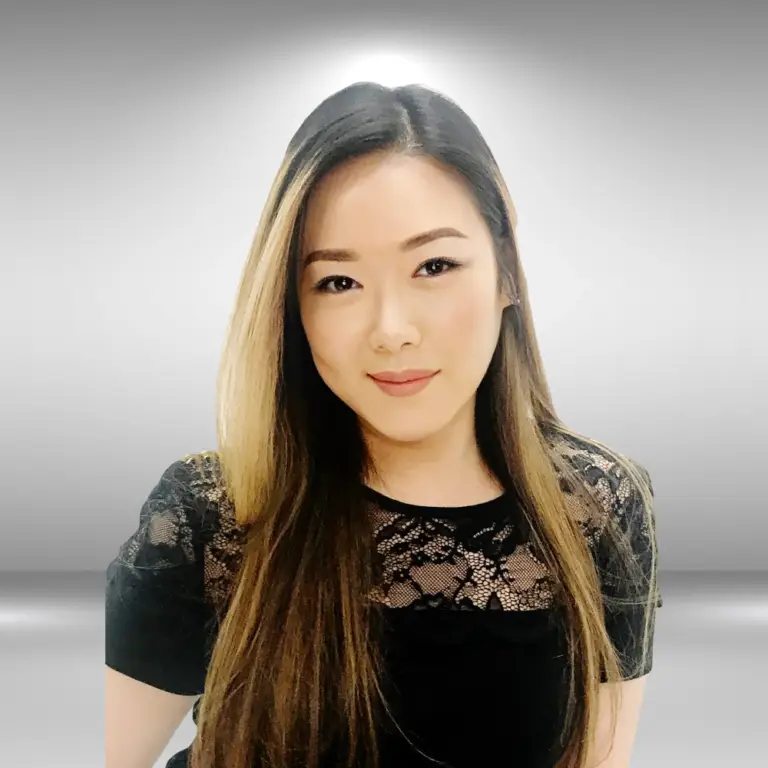 A poised woman with long, straight hair and a calm expression stands against a gradient grey background. She is wearing a black top with lace detailing on the shoulders and upper chest. Looking directly at the camera, she exudes the confidence of an influencer ready for the runway.