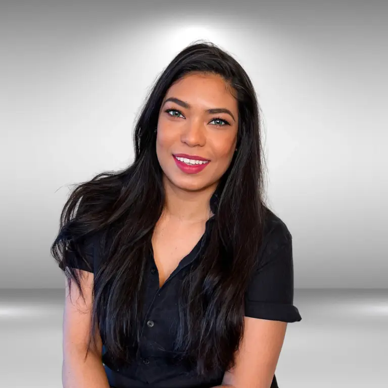 A talented woman with long dark hair and a black top smiles warmly at the camera. The background is a simple, gradient gray.