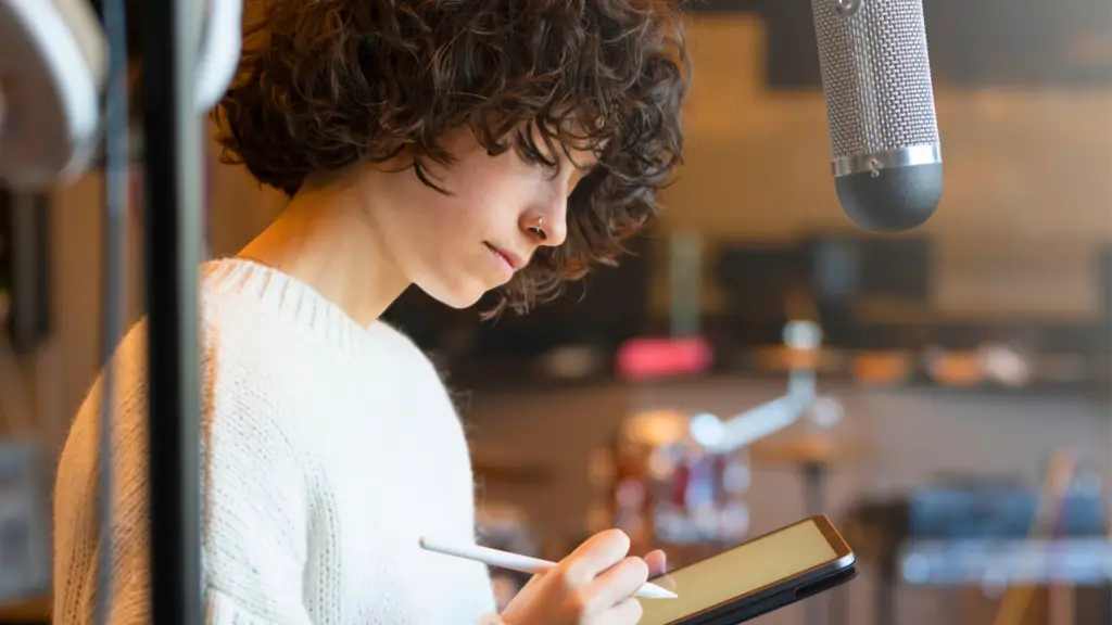 Person writing on iPad in a recording studio