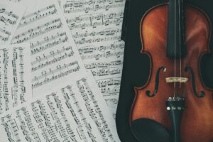 pieces of sheet music lying on a table next to a violin